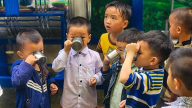 A group of children drink cups of water