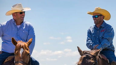 Two friends on horseback having a conversation