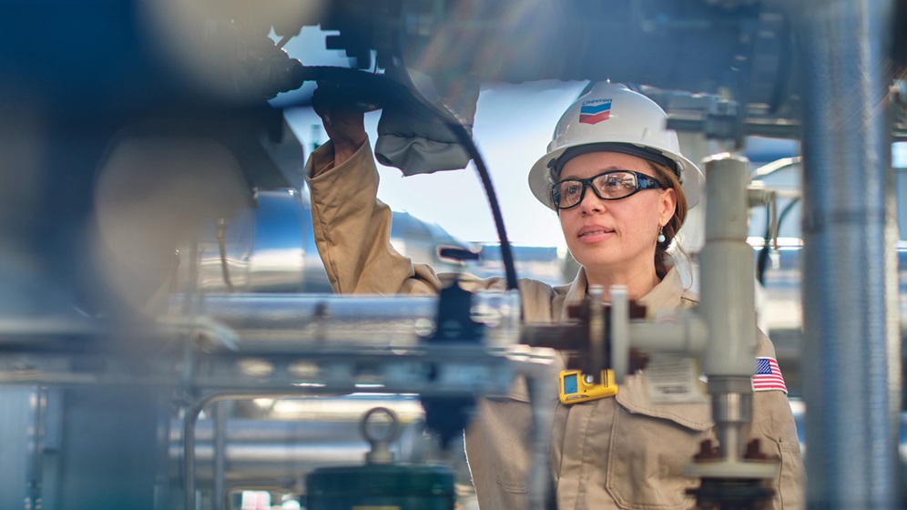 Woman in hard hat inspecting pipes.